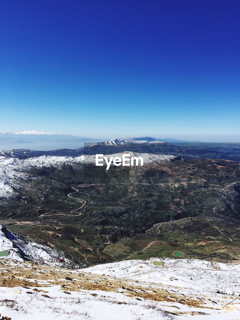 Snow covered landscape against clear blue sky