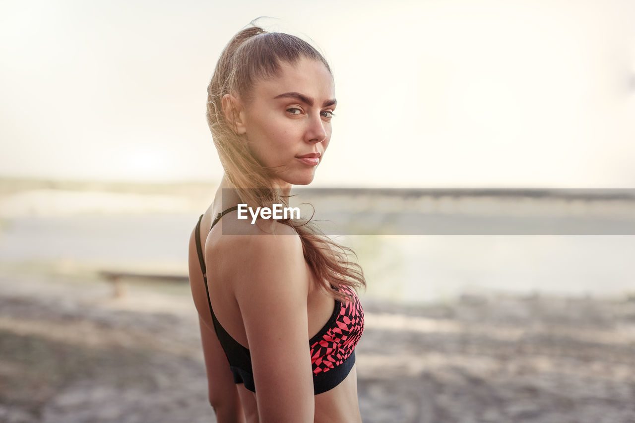 Side view portrait of woman in sports clothing standing at beach