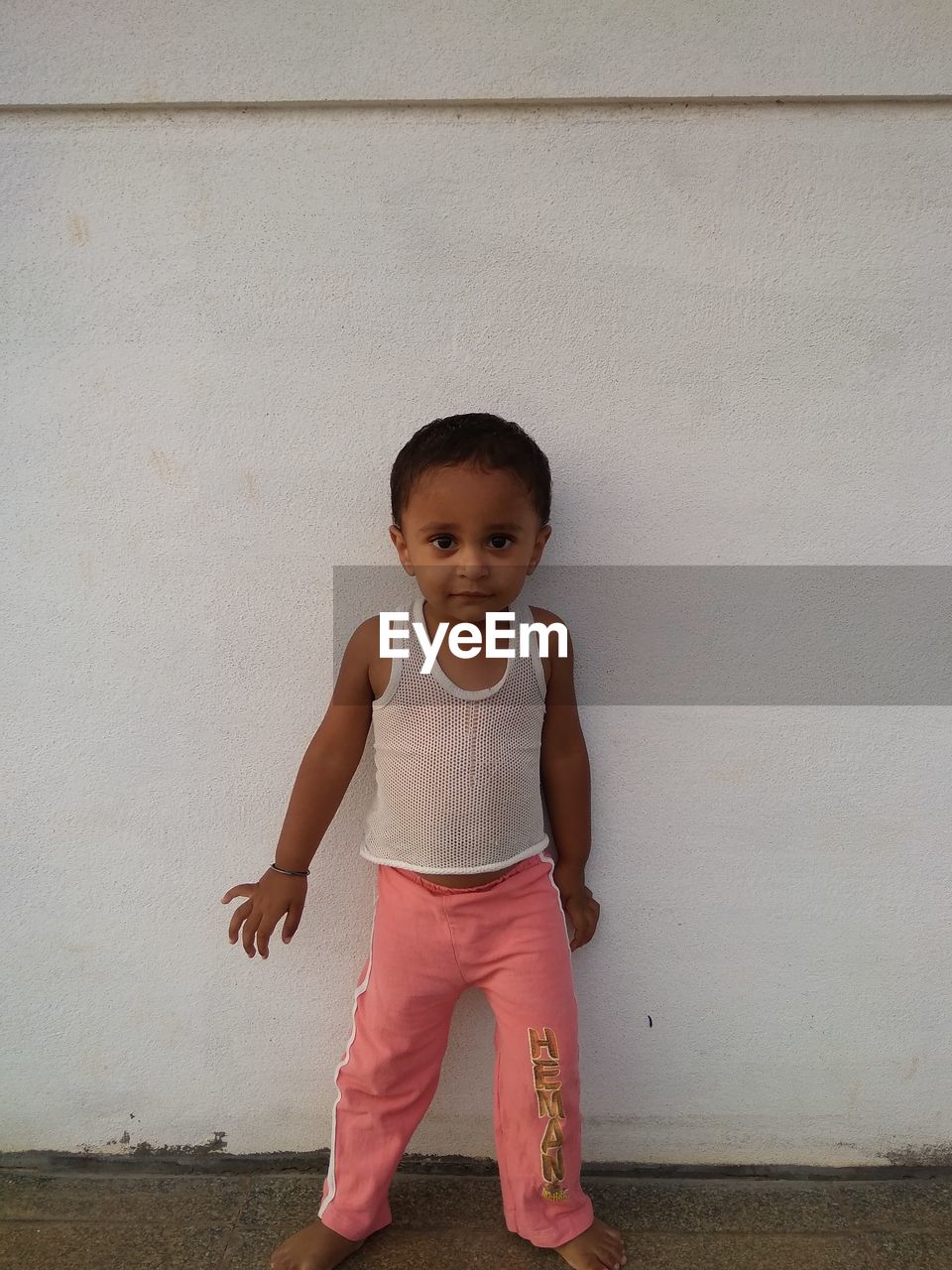 Portrait of baby boy standing against white wall