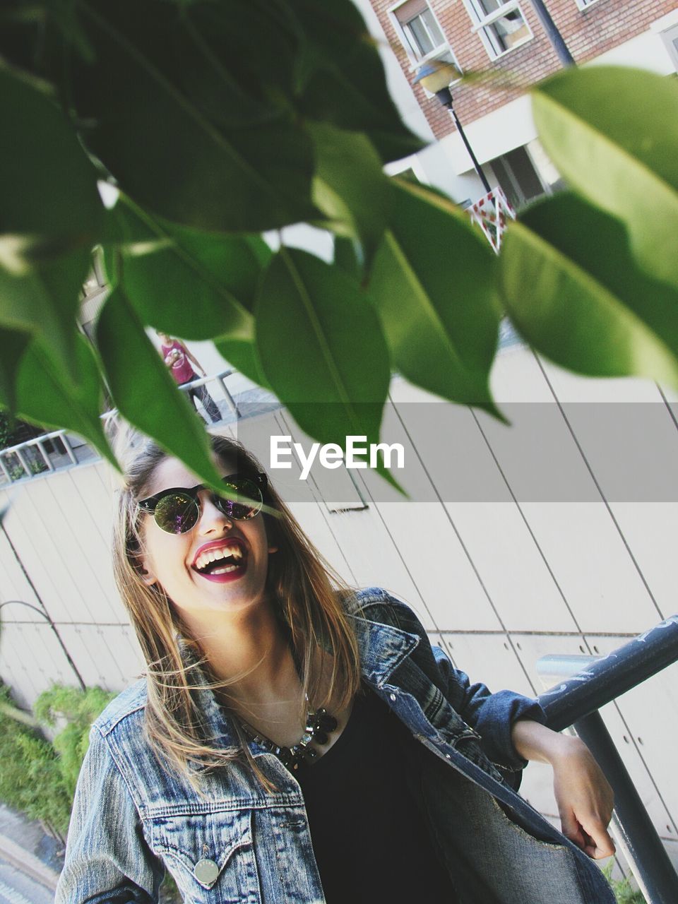 Young woman laughing while standing at balcony