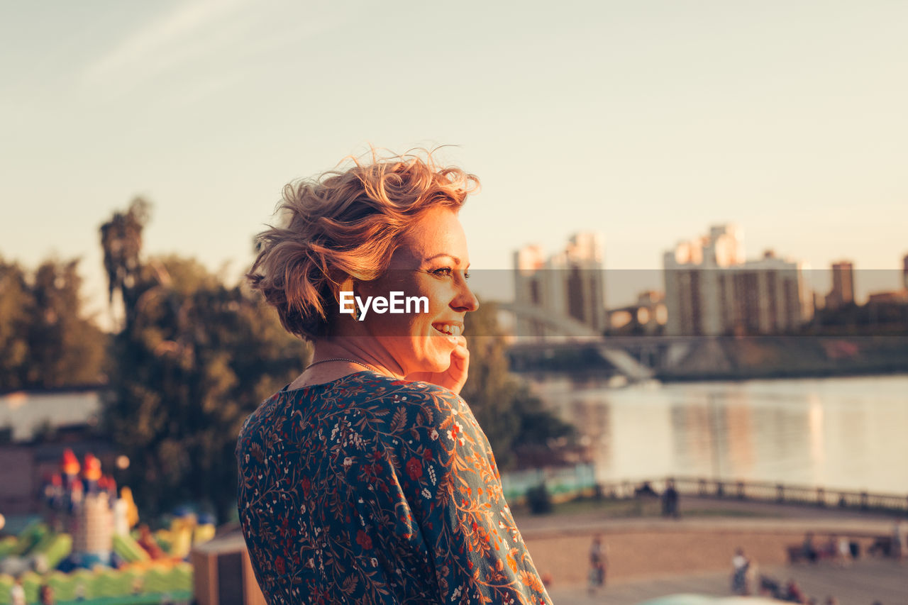 Young woman looking away and smiling during sunset