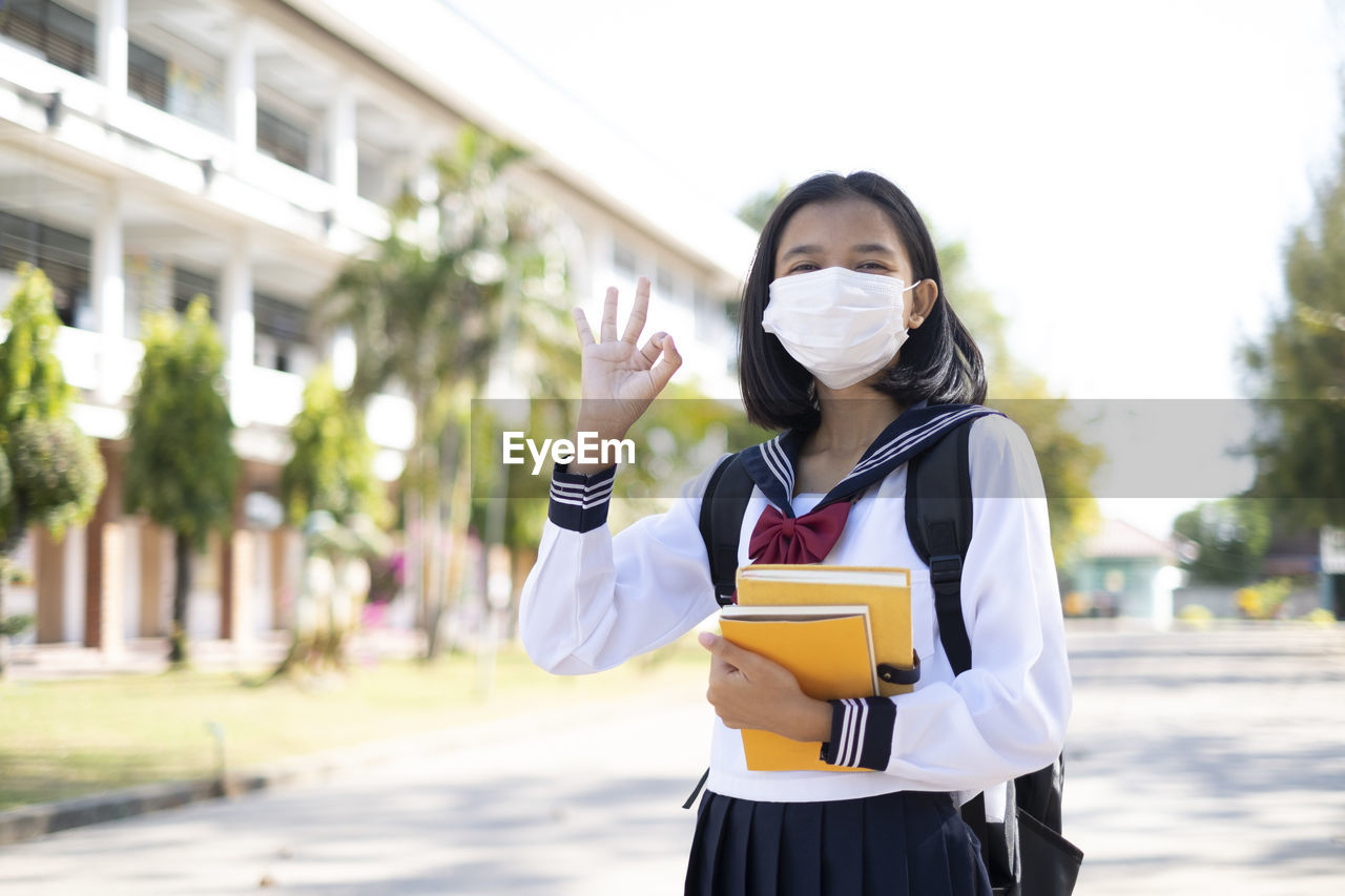 Portrait of girl wearing mask standing outdoors
