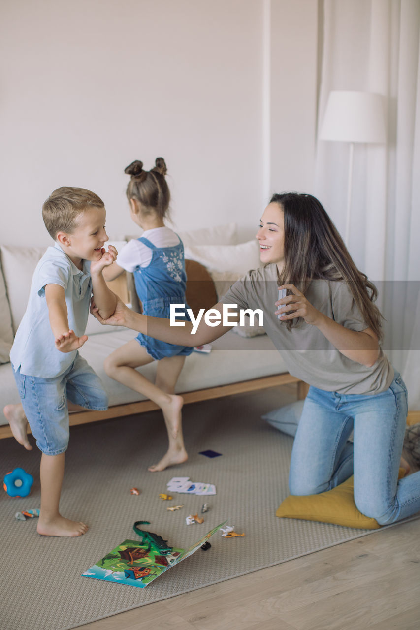 Teacher playing educational games with a little girl and a boy in modern playroom.