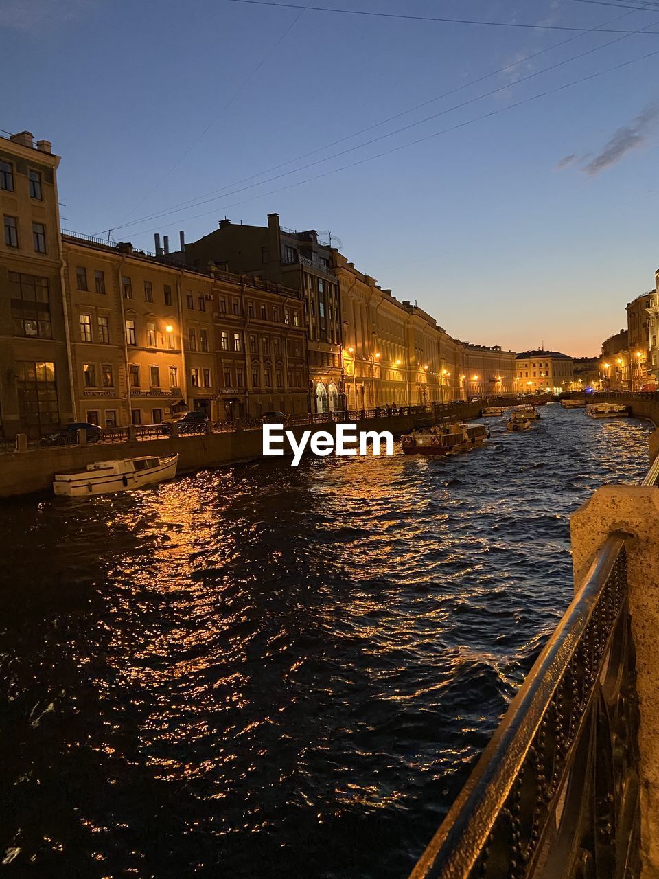 RIVER BY ILLUMINATED CITY BUILDINGS AT NIGHT