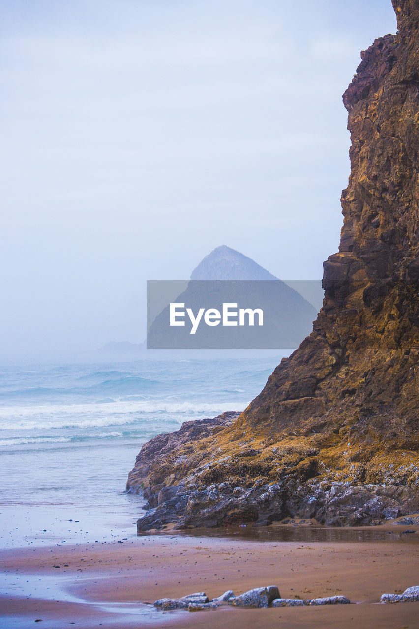 Rock formation at beach against sky