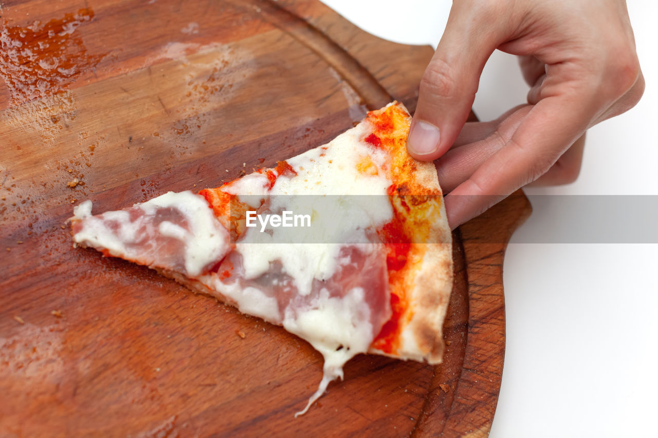 Man took last one slice of delicious italian pizza. in frame hand taking slice of hot pizza with ham
