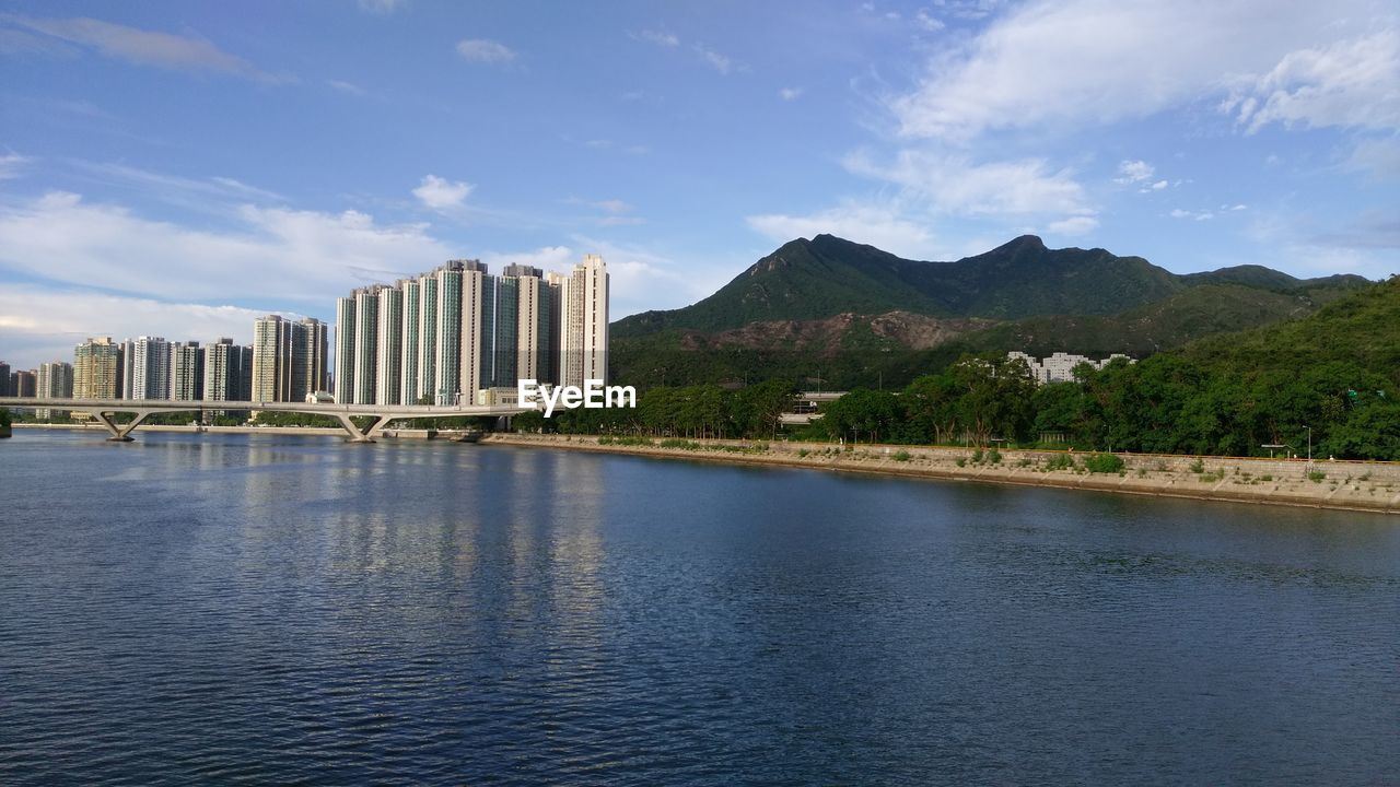 Scenic view of river by buildings against sky