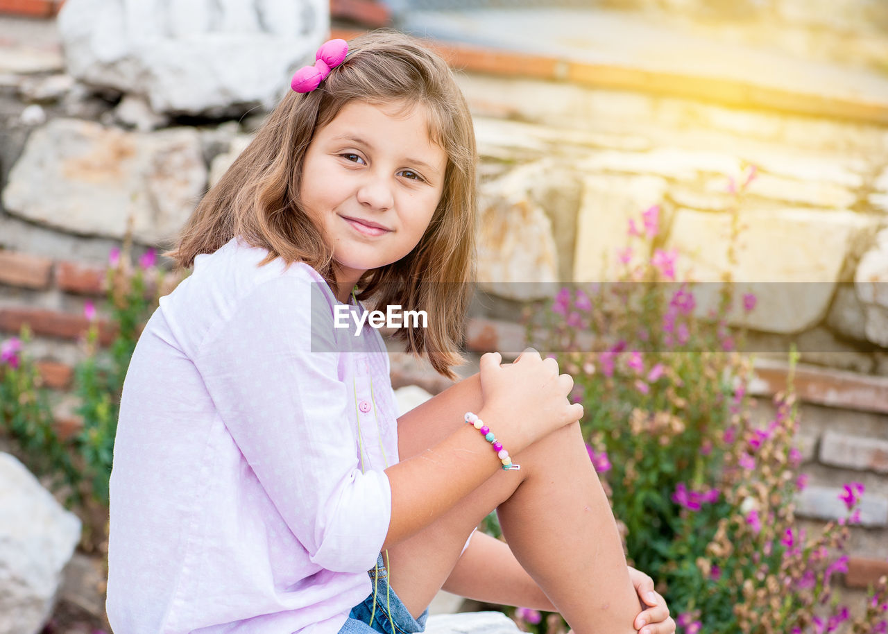 PORTRAIT OF SMILING GIRL WITH PINK FLOWERS