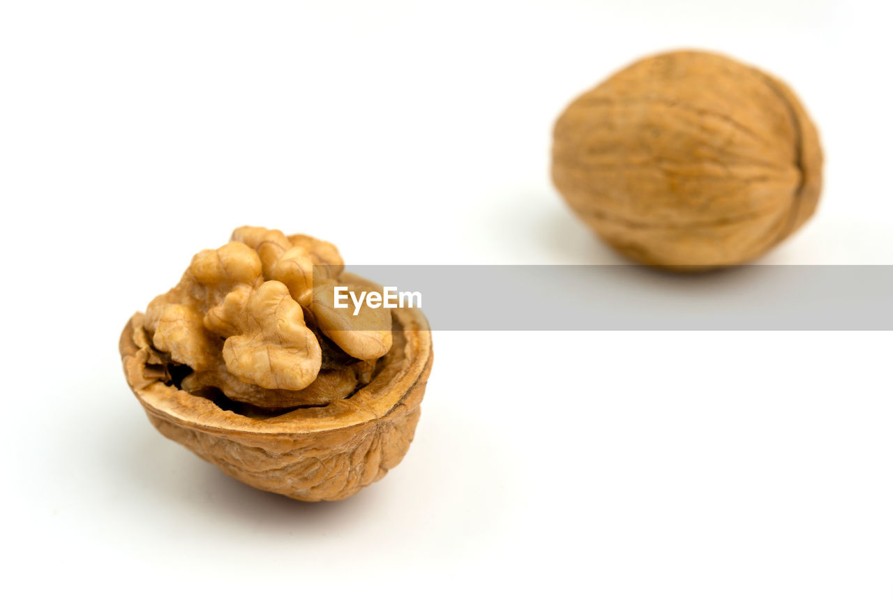 Walnut opened with visible kernel and opened walnut out of focus in the background.