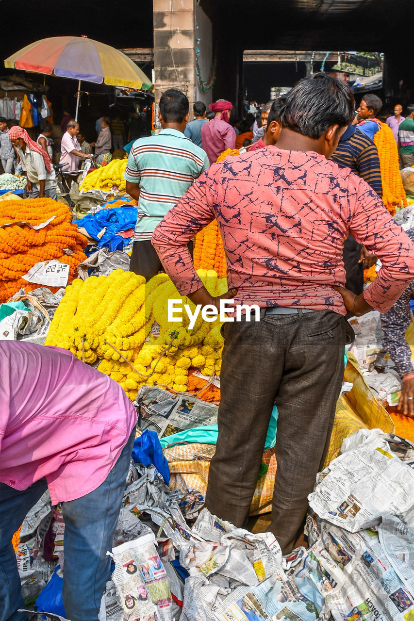 REAR VIEW OF PEOPLE WALKING AT MARKET STALL