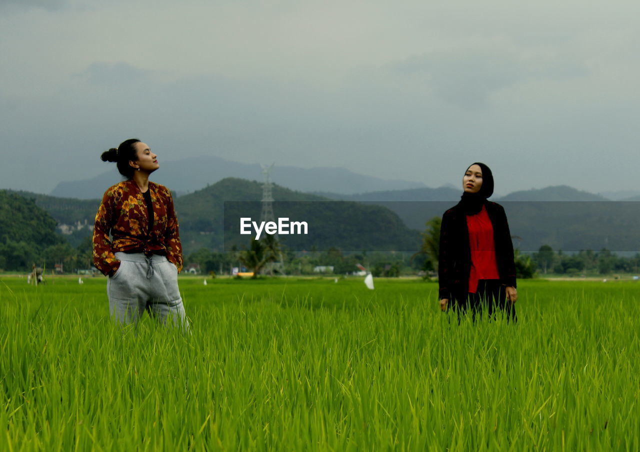 Women standing on field against sky