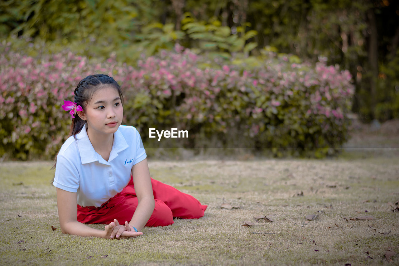 Beautiful young woman sitting on grassy field at park