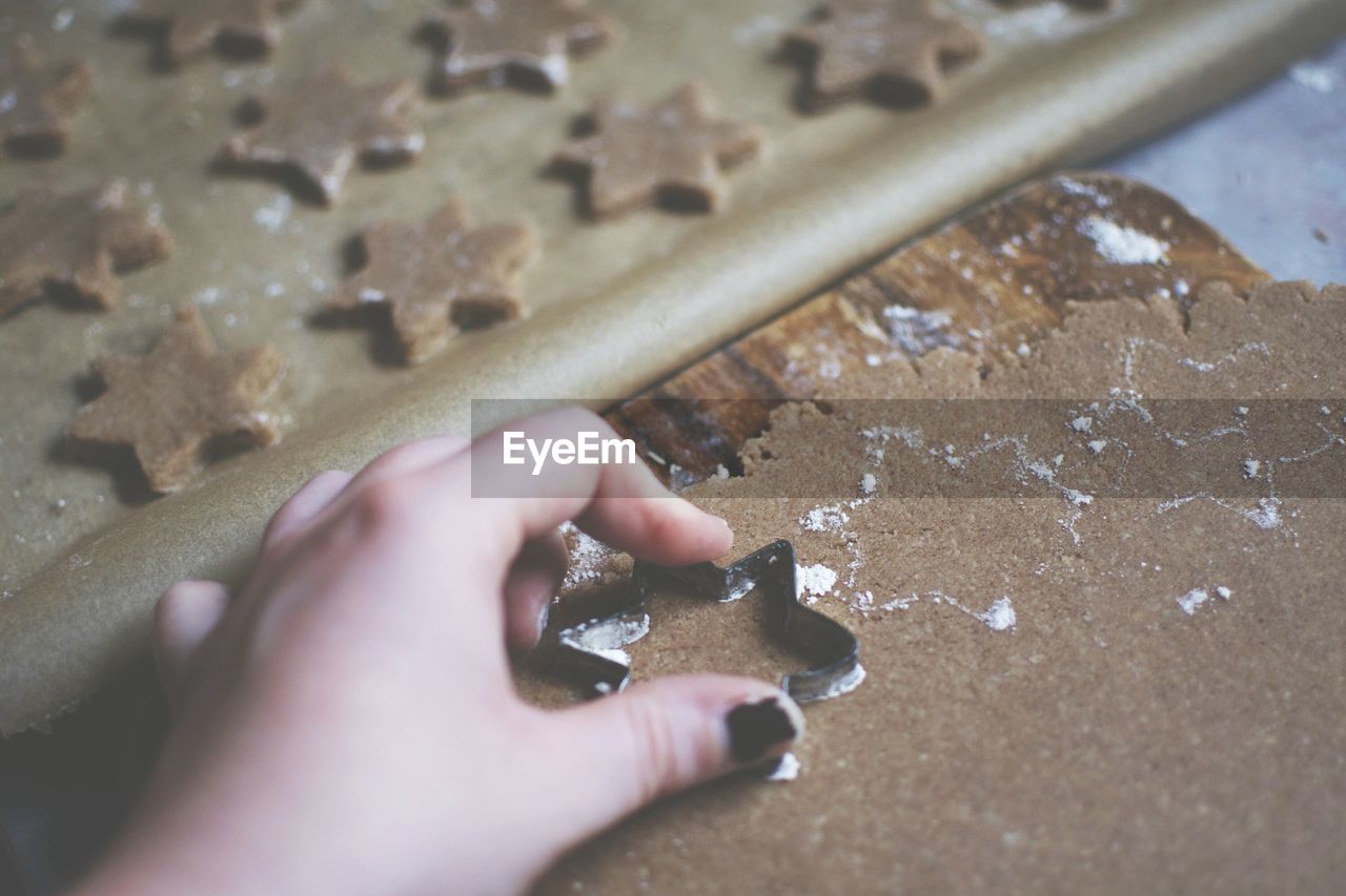 Cropped hand of woman making star shape cookie on table