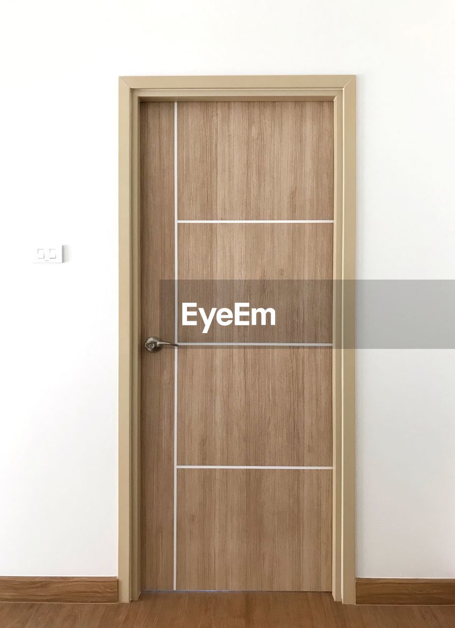 VIEW OF WOODEN DOOR WITH WHITE WALL