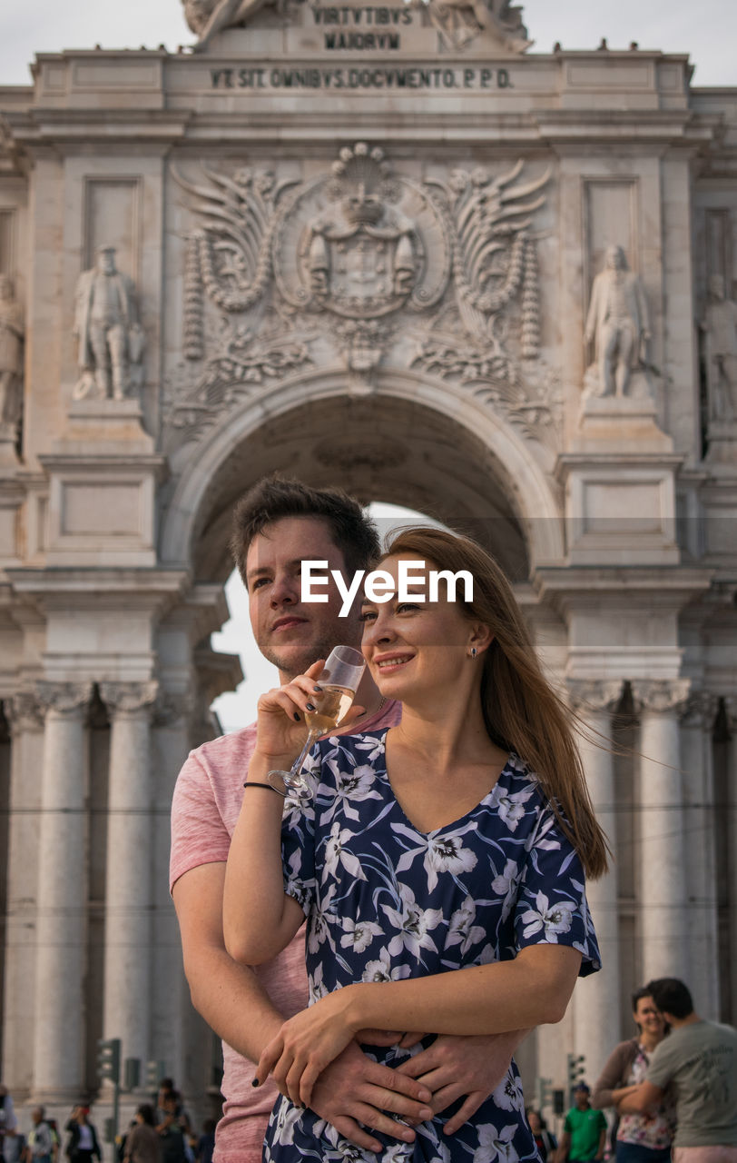 Smiling couple standing against building