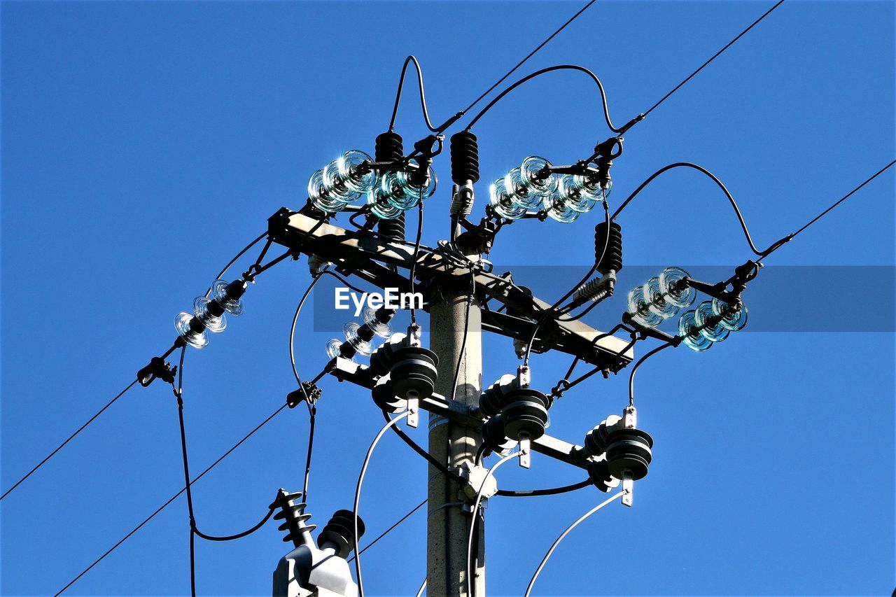 Concrete and steel pole with electrical cables, against the blue sky background.