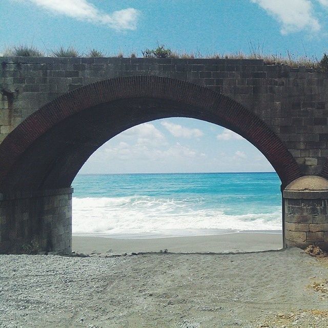 Arch bridge against beach water