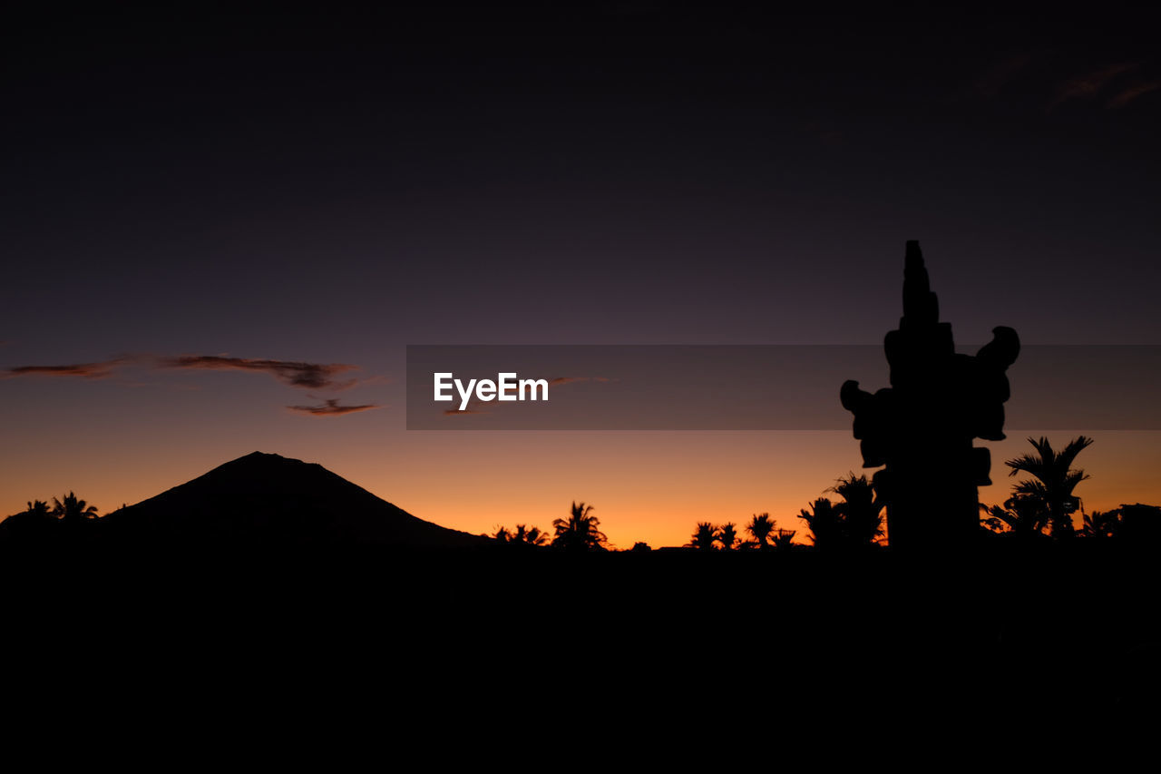 SILHOUETTE STATUE AGAINST ORANGE SKY