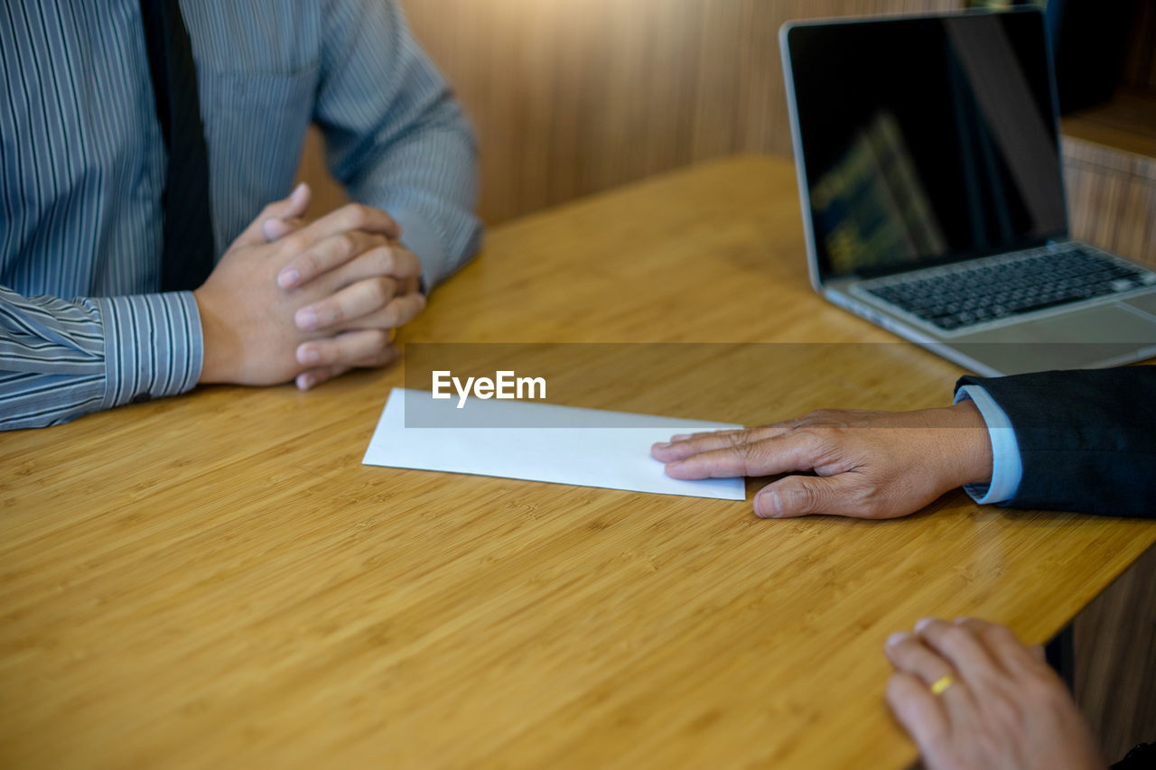 Businessman giving envelope to candidate on table