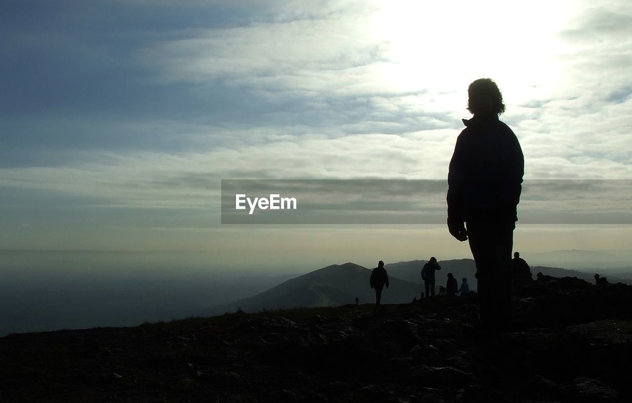 MEN STANDING ON MOUNTAIN AGAINST SKY