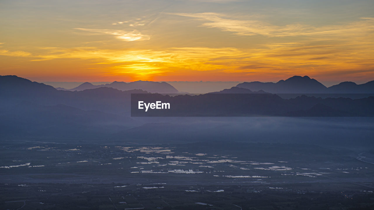 Scenic view of silhouette mountains against orange sky