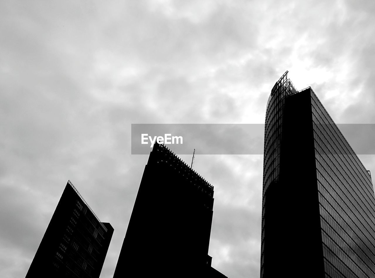 Low angle view of tall buildings against cloudy sky