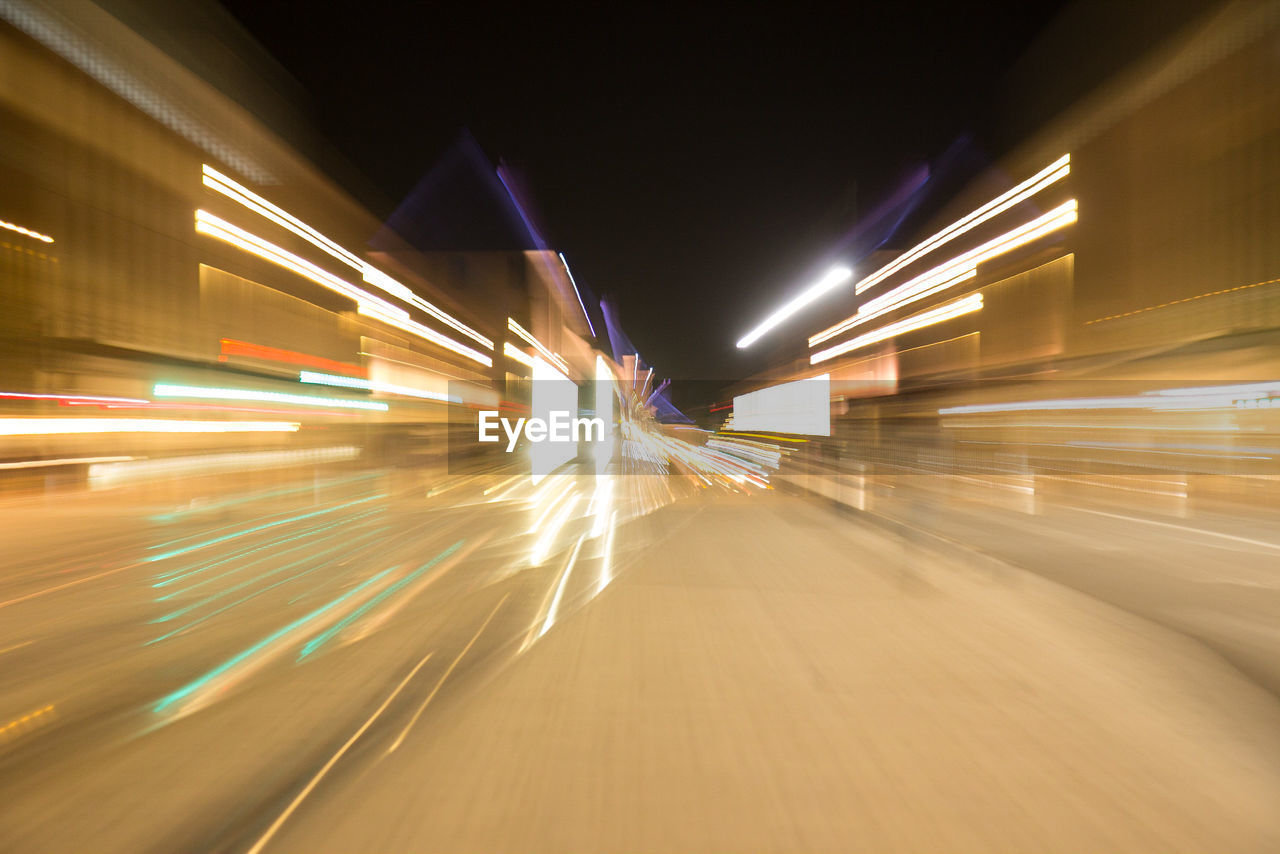 BLURRED MOTION OF LIGHT TRAILS ON ROAD IN CITY AT NIGHT