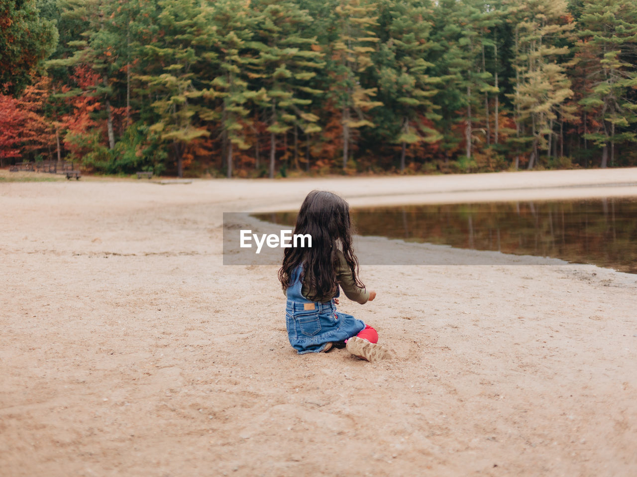 Girl playing by lake on a lovely autumn or fall day