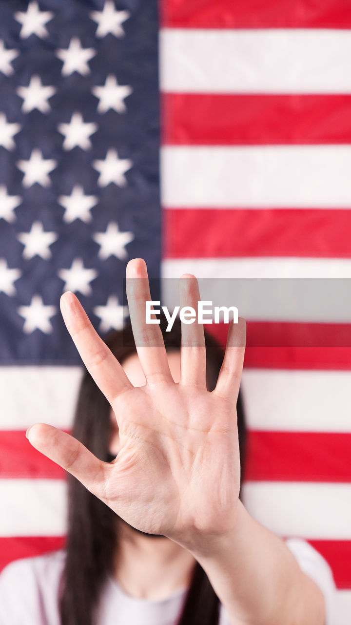 Young woman stretch out her palm to camera anti domestic violence american flag on background. 