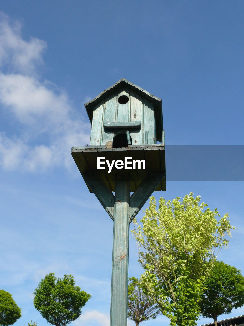 Low angle view of birdhouse against blue sky