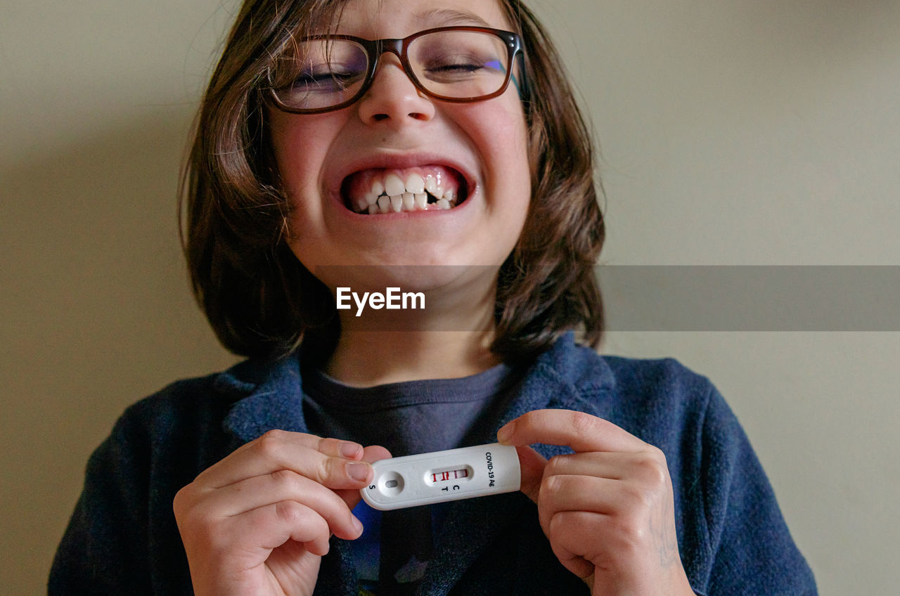 Portrait of a kid holding a positive covid test