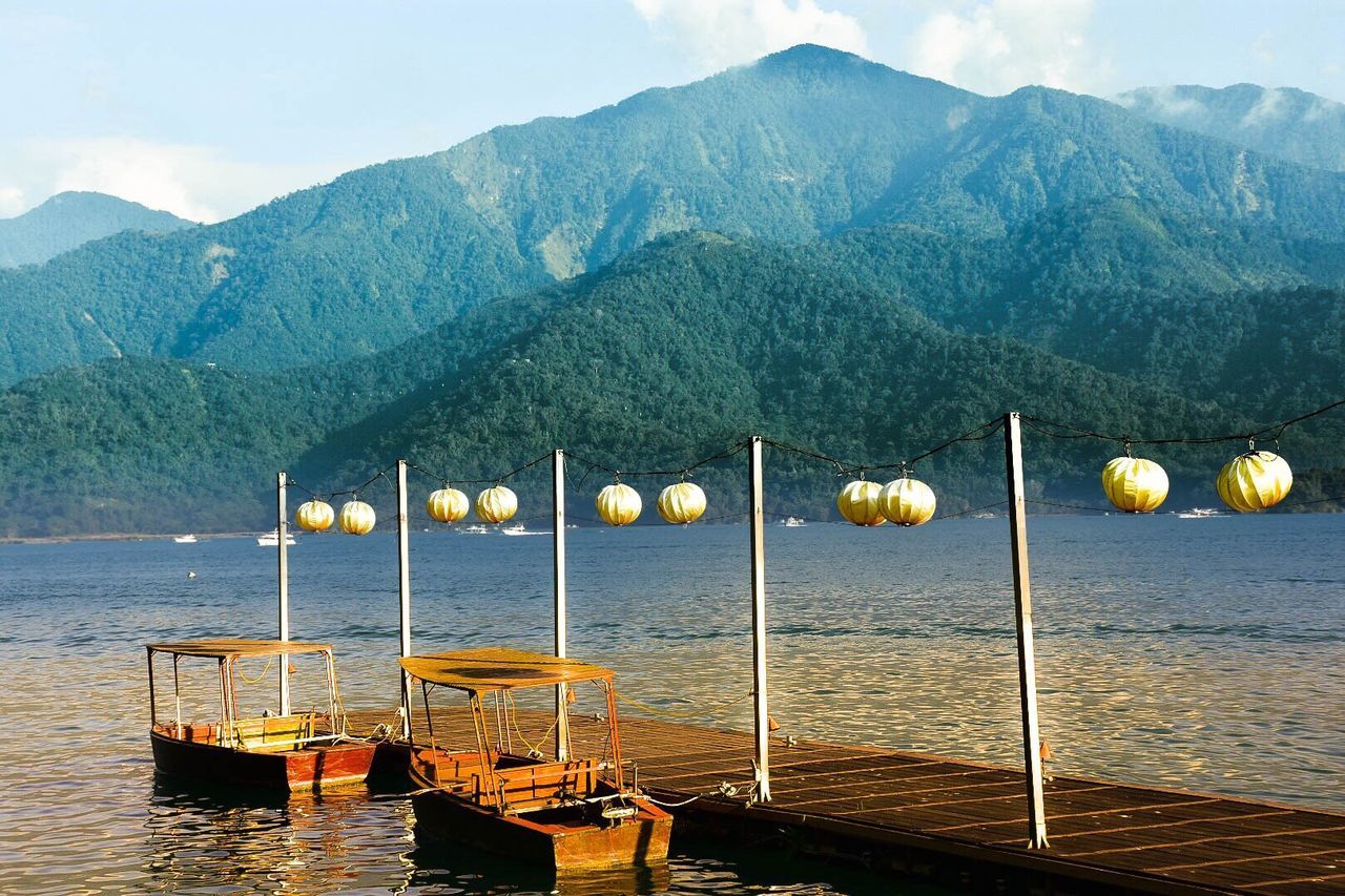 View of boats in sea against mountain range