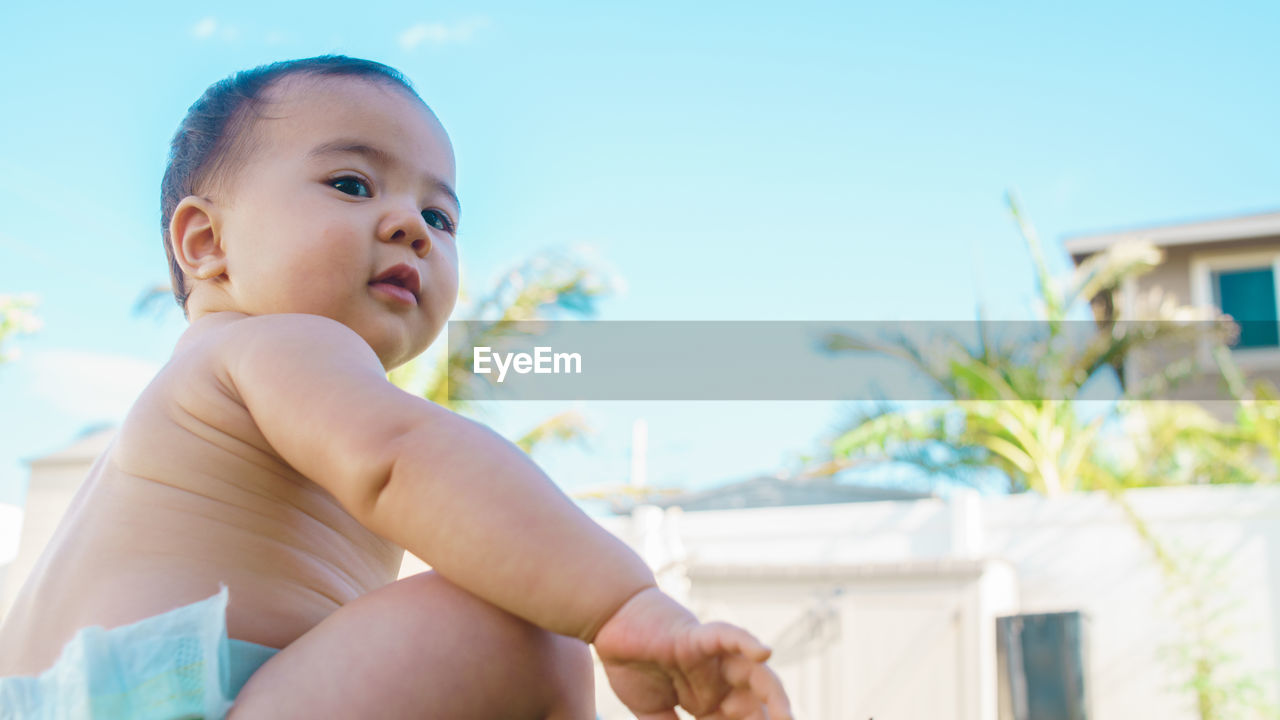 Low angle view of baby sitting against sky