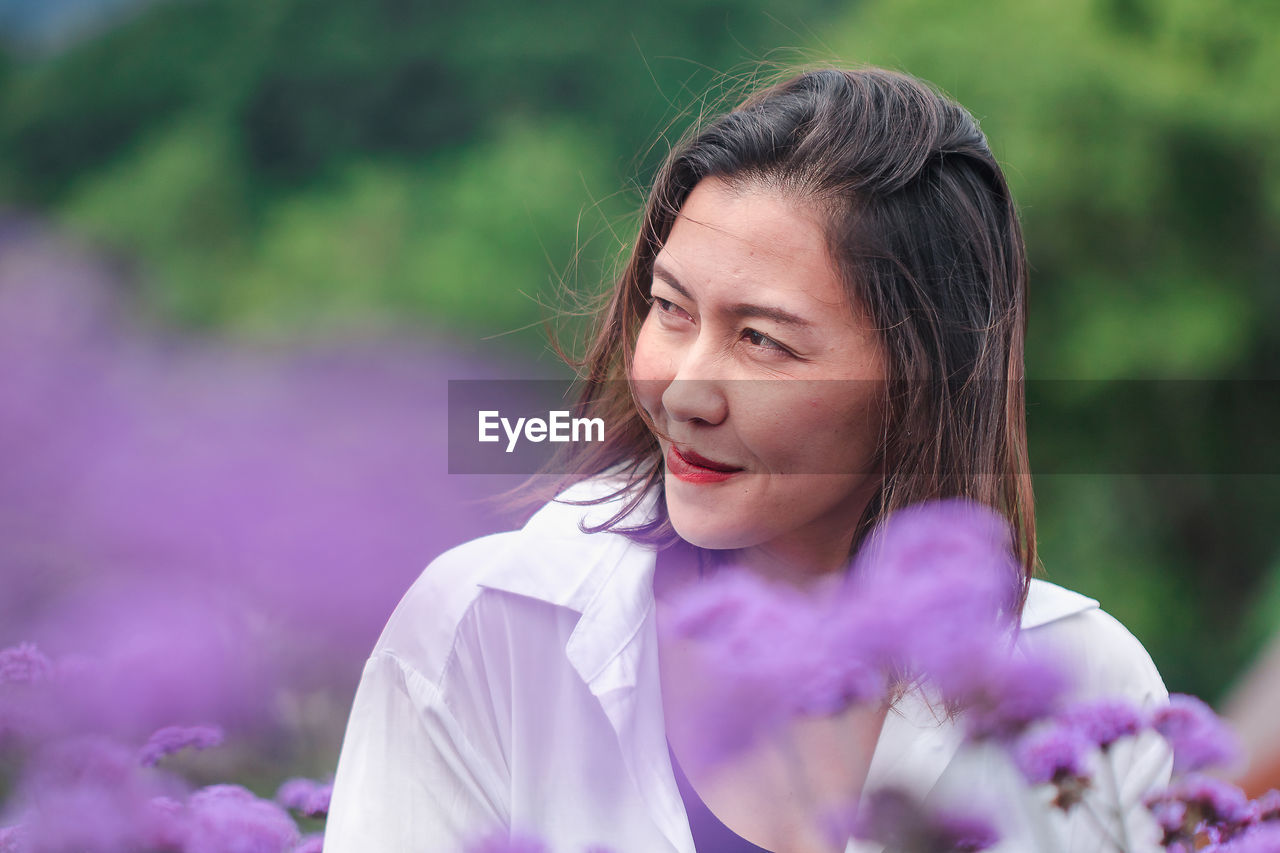 Woman amidst purple flowers looking away