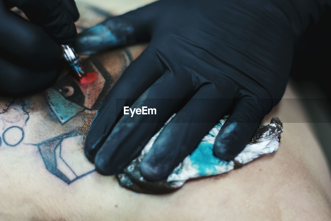 Cropped hands of male artist tattooing on customer