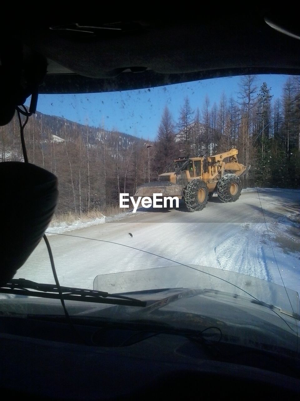 Bulldozer on road seen through vehicle windshield