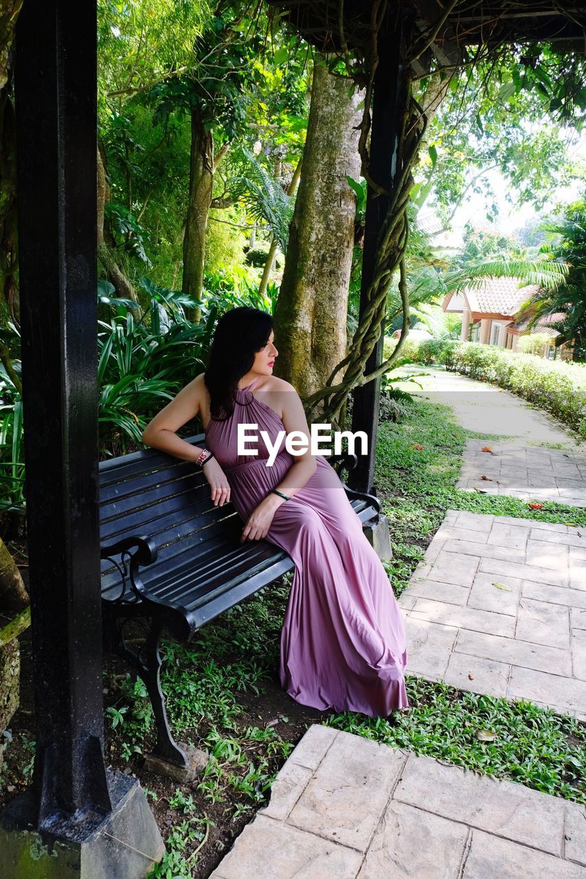 Mid adult woman sitting on bench in park