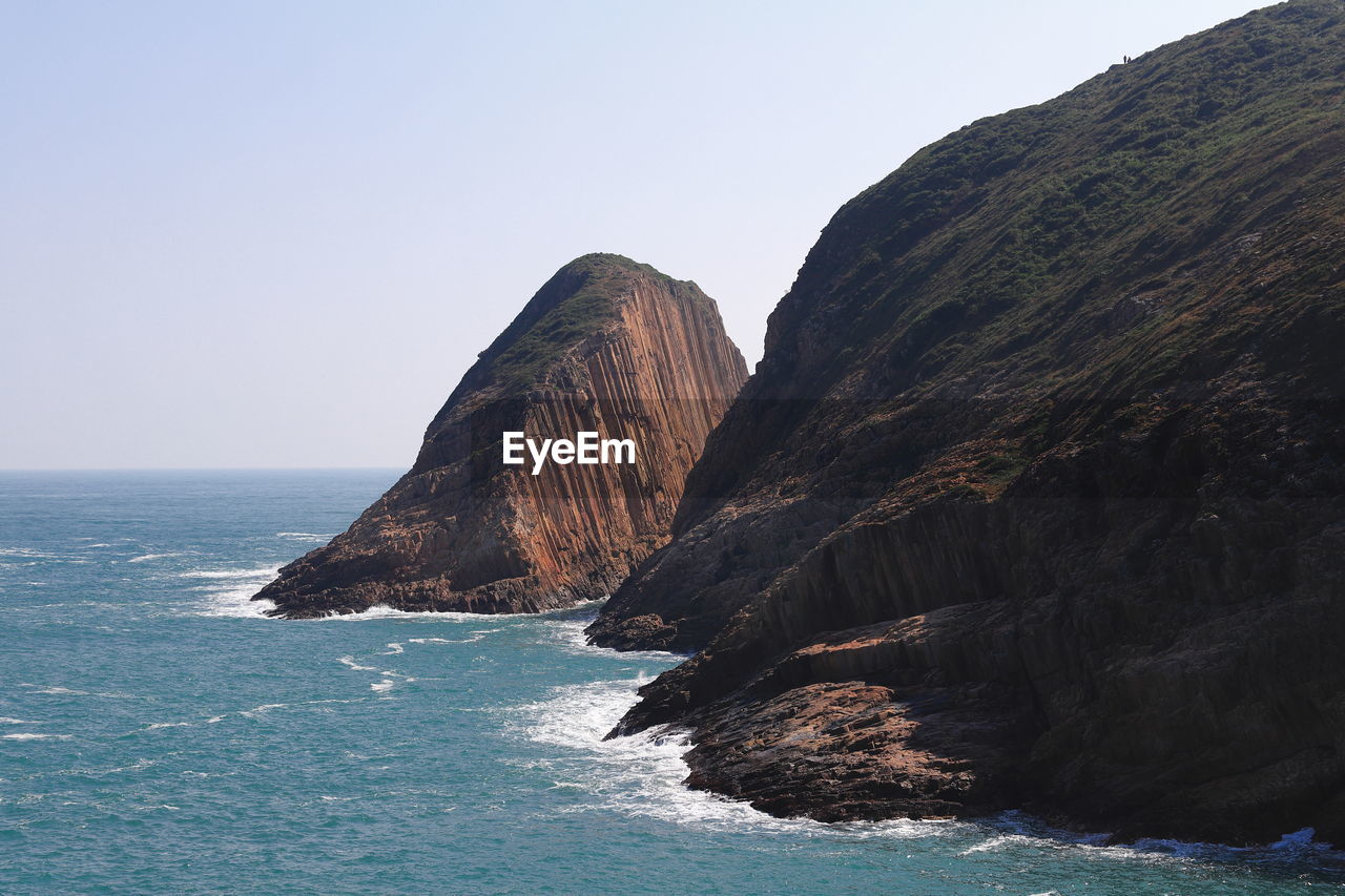 Scenic view of sea and mountains against clear sky