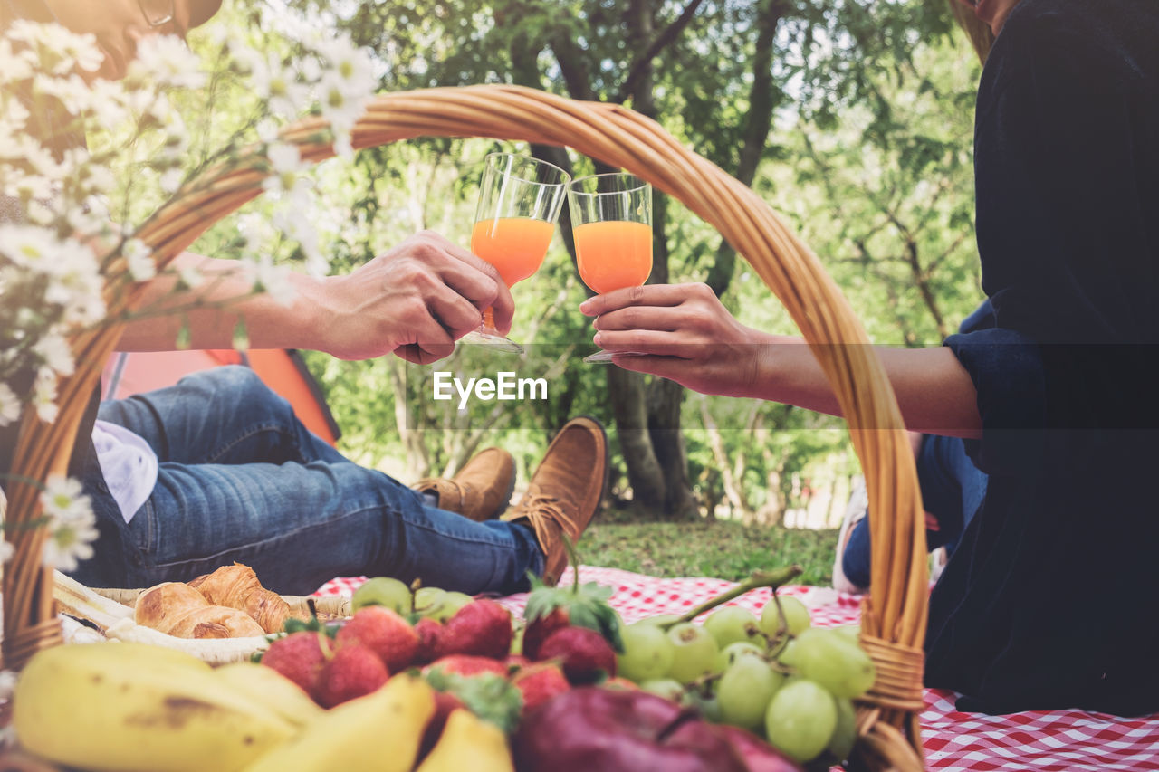 Midsection of couple toasting juice glasses