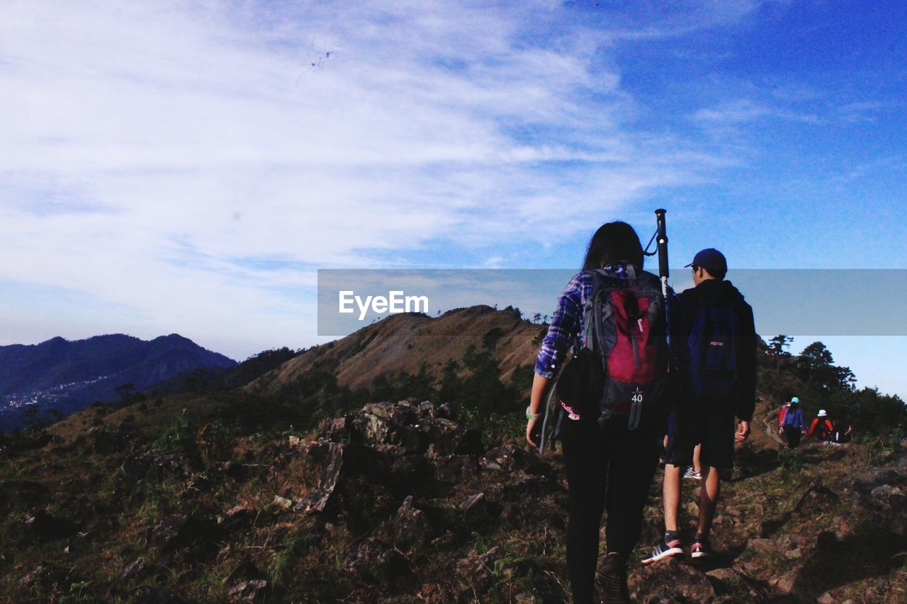 REAR VIEW OF MEN WALKING ON MOUNTAIN