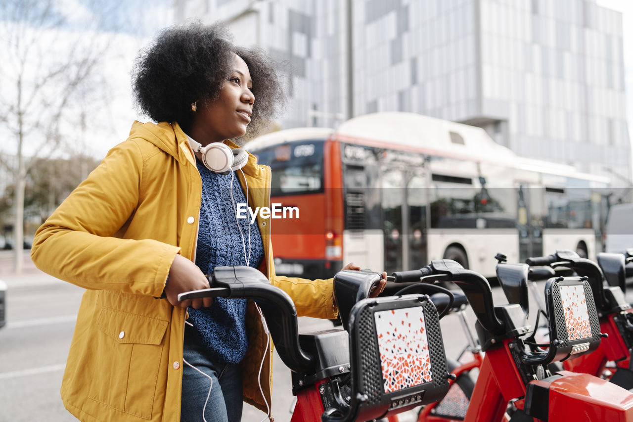 Thoughtful woman standing at bicycle parking station