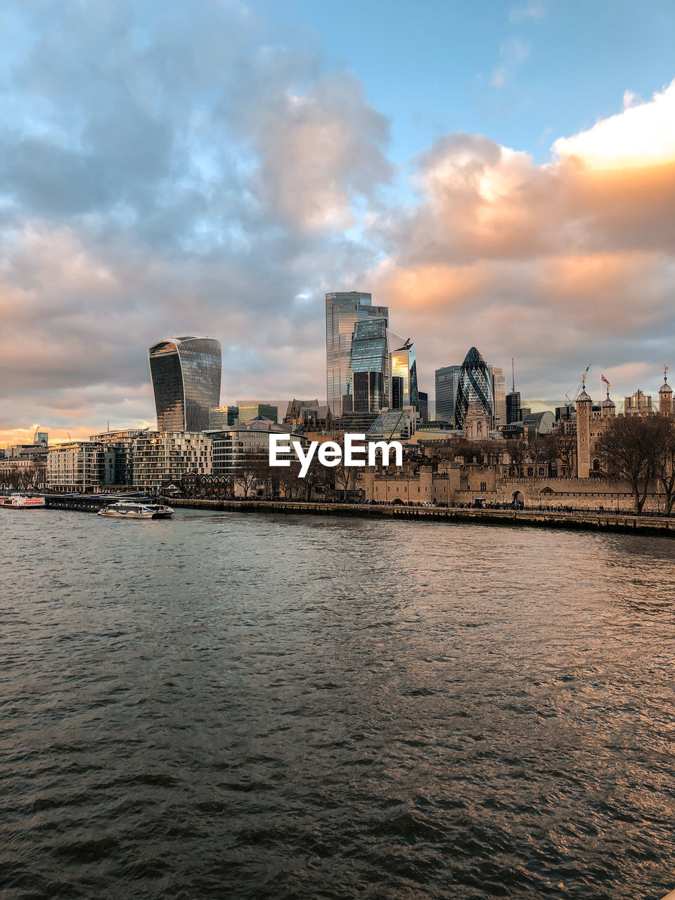 River by buildings against sky during sunset