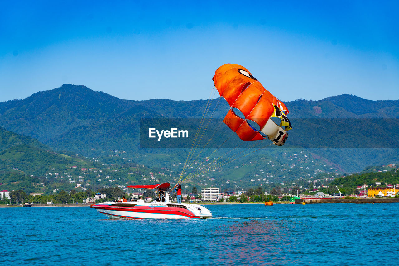 BOAT IN SEA AGAINST MOUNTAIN