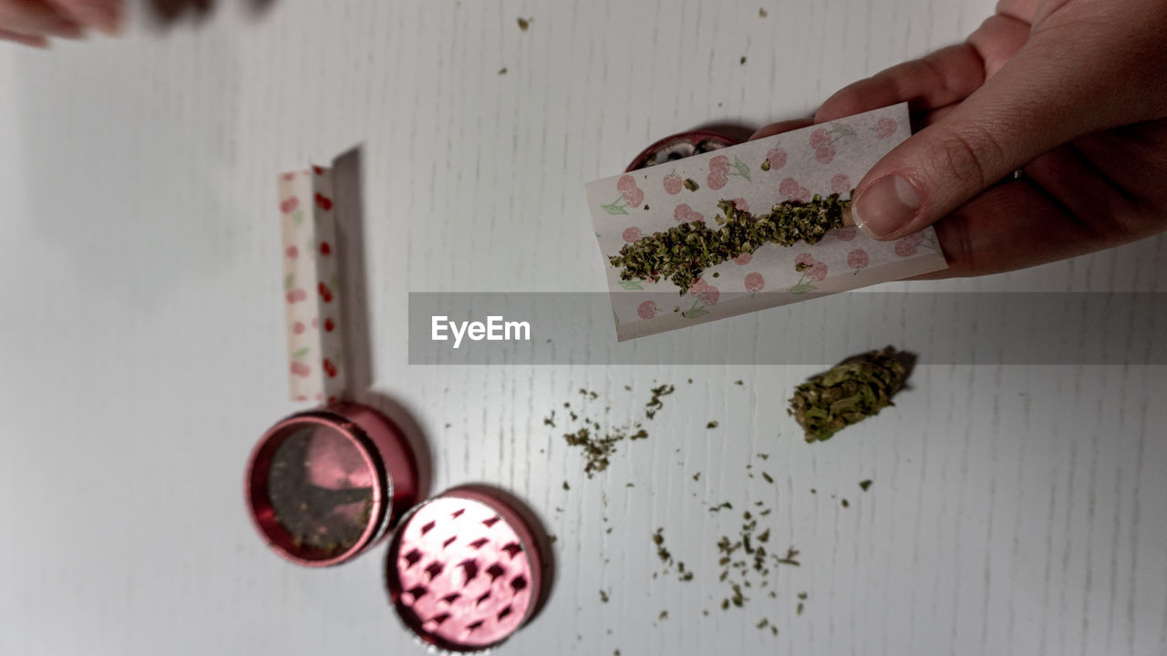 Cropped hand holding marijuana on table