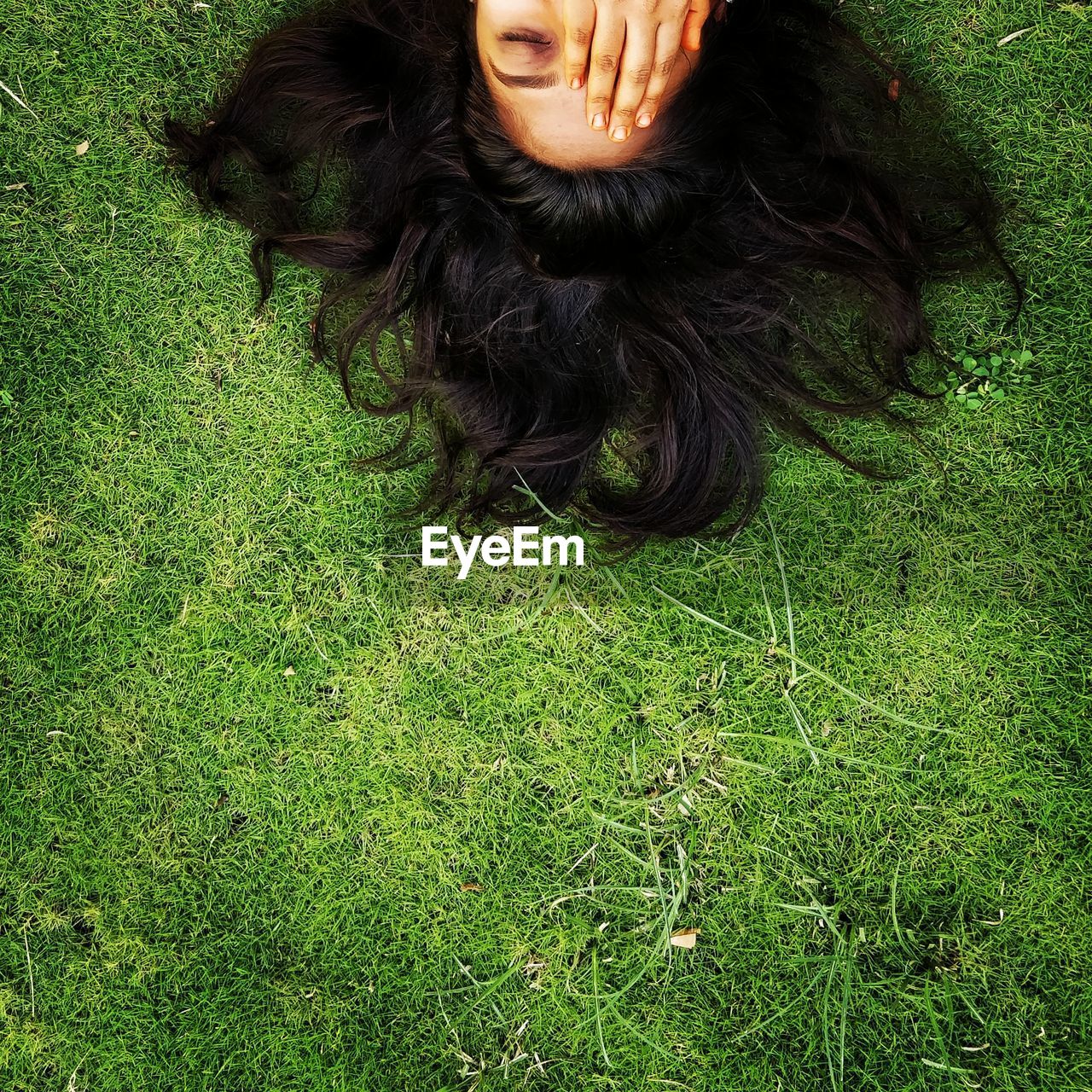 HIGH ANGLE PORTRAIT OF WOMAN LYING ON GRASS