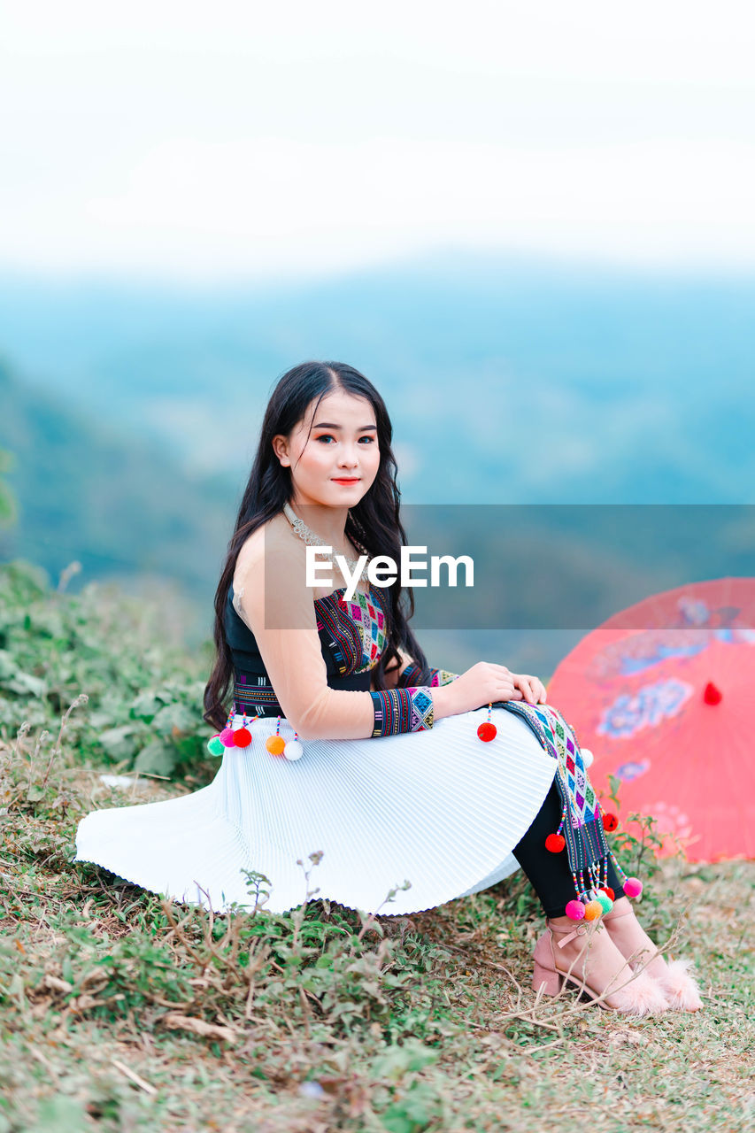 Portrait of smiling young woman sitting on land