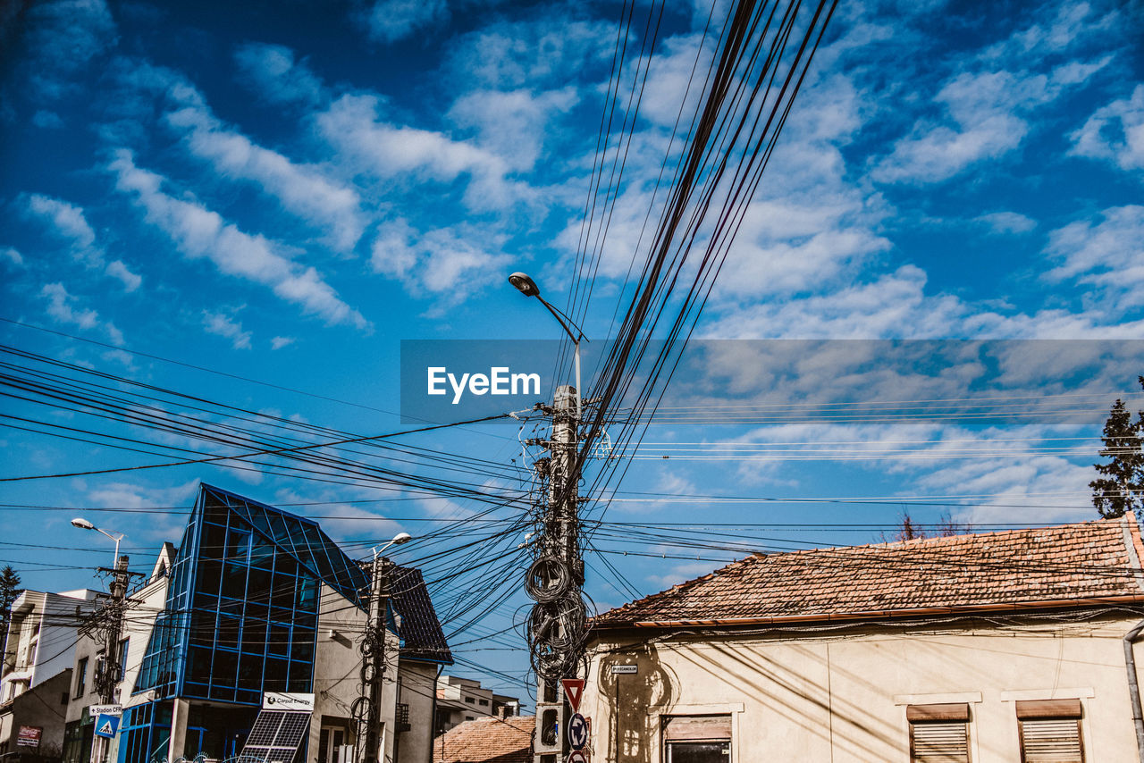 Low angle view of buildings with pylon against cloudy sky