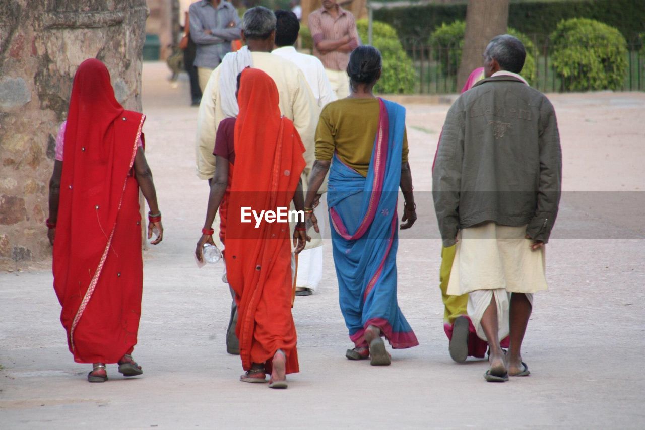 REAR VIEW OF PEOPLE STANDING ON STREET