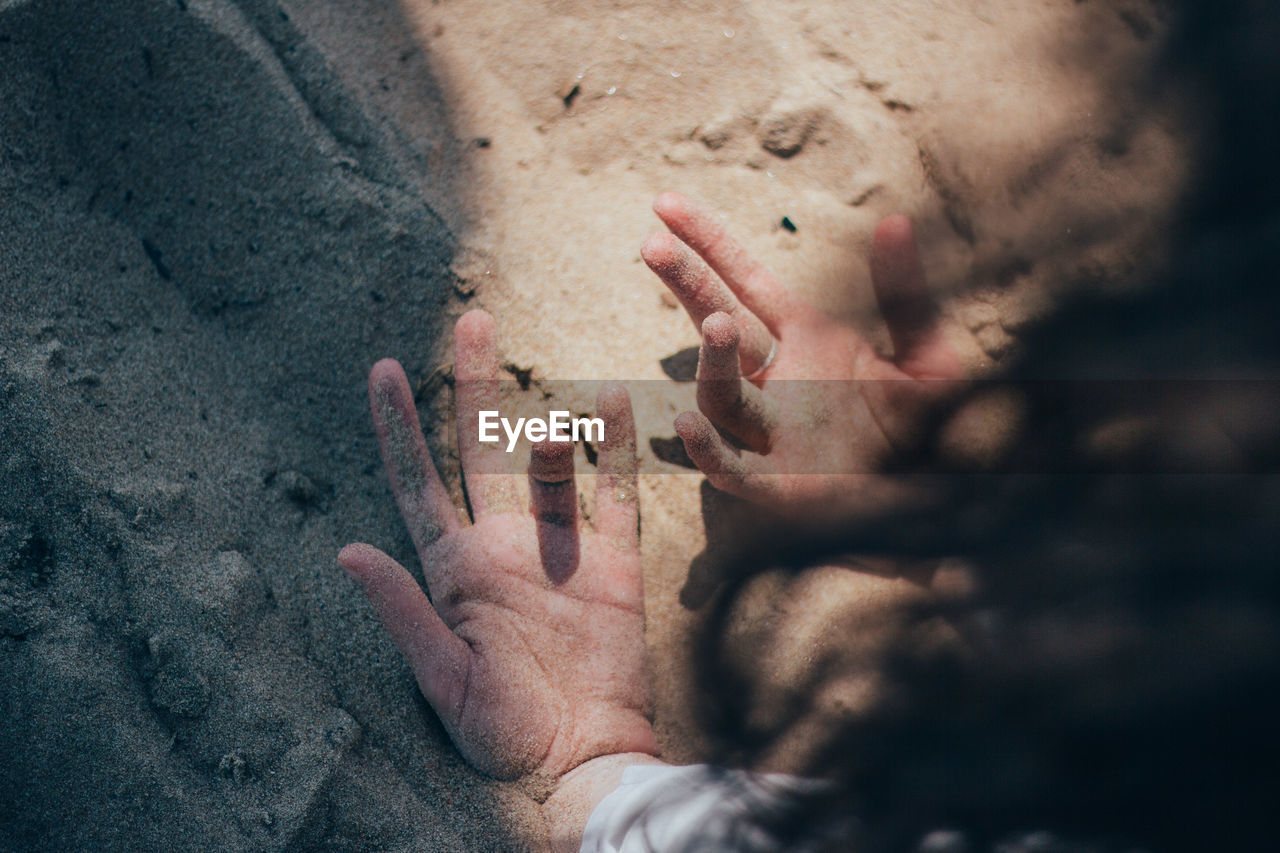 Cropped hands of woman on sand at beach