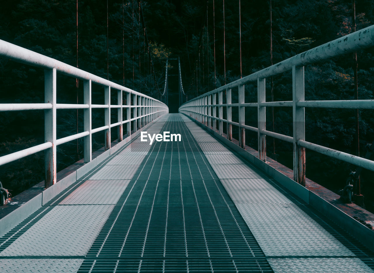 Empty footbridge against trees in forest